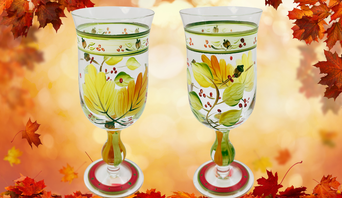 Autumn Leaves Wine Glass shown from two sides with hand-painted fall foliage against a glowing autumn leaf background