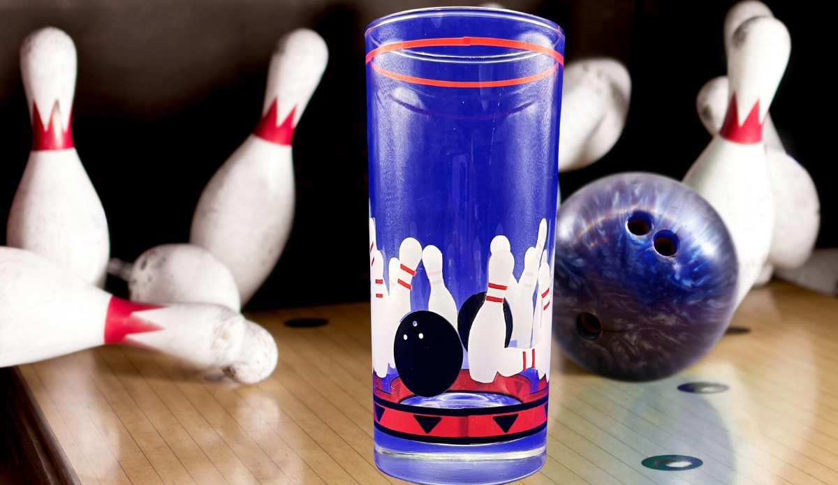 Vintage Bowling Drinking Glass displayed on bowling lane beside scattered pins and blue marbled bowling ball