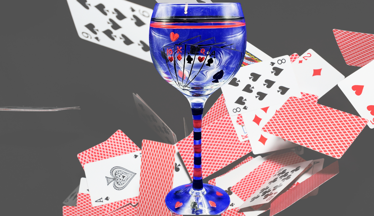 Hand Painted Playing Cards Wine Glass displayed among floating poker cards with blue bowl and red striped stem
