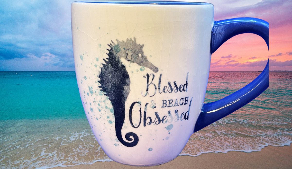 Blessed Beach Obsessed Seahorse Mug displayed against turquoise ocean water and colorful beach sunset