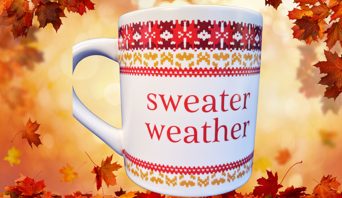 Sweater Weather Knit Pattern Mug displayed against a glowing autumn background with colorful falling leaves