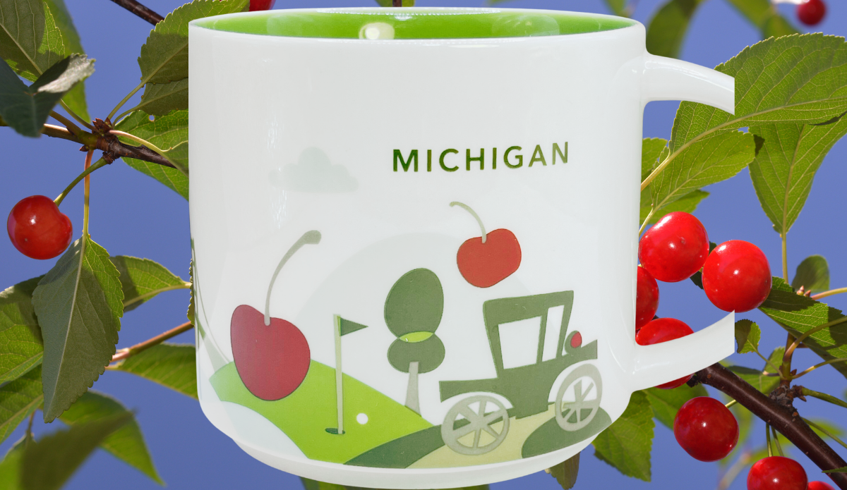 Starbucks Michigan Mug displayed among red cherries and green leaves against a blue sky