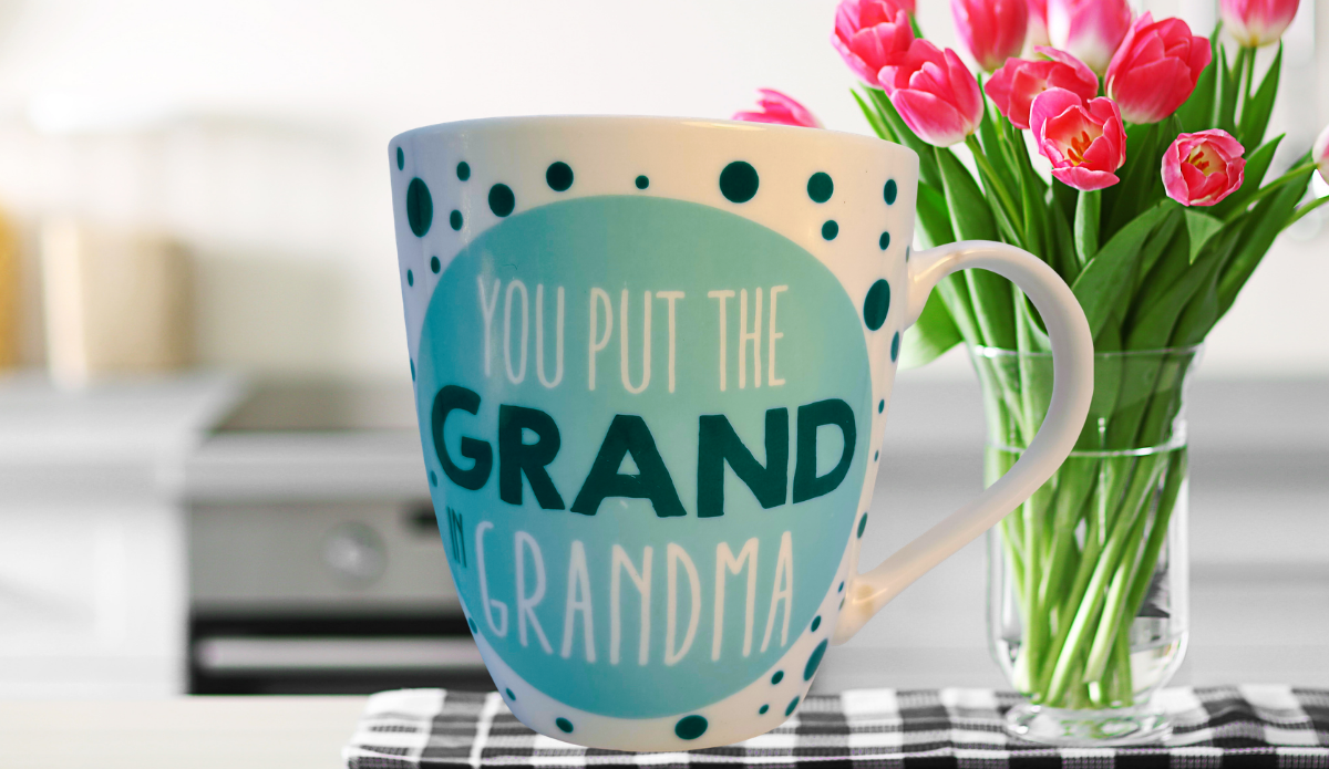 You Put The Grand In Grandma mug with pink tulips on table