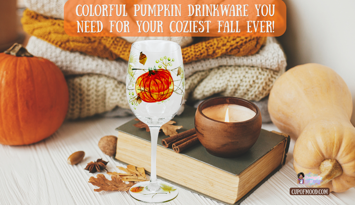 Pumpkin drinkware featuring a hand painted pumpkin wine glass beside pumpkins, a candle, books, cinnamon sticks, and cozy fall blankets
