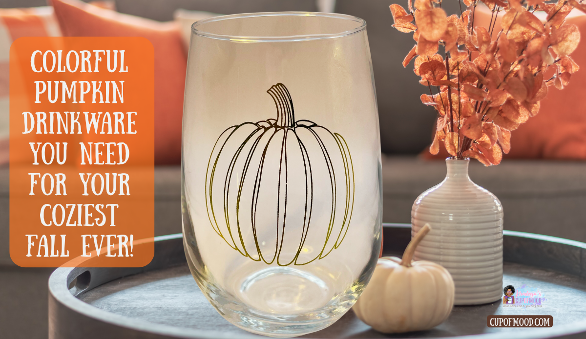 Stemless pumpkin wine glass with outlined pumpkin design displayed with orange pillows, fall flowers, and a small cream pumpkin