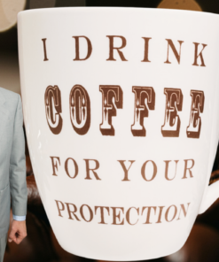Oversized I Drink Coffee For Your Protection Mug displayed beside a frazzled coffee drinker