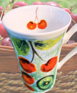 Roy Kirkham Cherry Kiwi Bone China Mug styled in front of a basket of fresh cherries outdoors