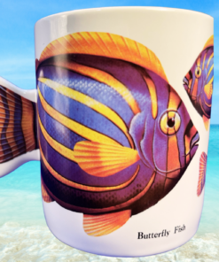 butterfly fish mug styled on sandy beach with turquoise ocean water and bright tropical sunlight