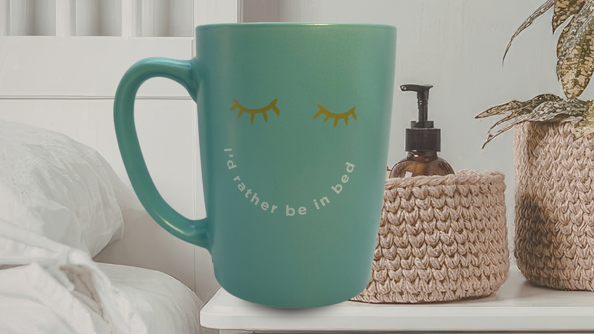I’d Rather Be In Bed Mug styled on bedside table with soft linens