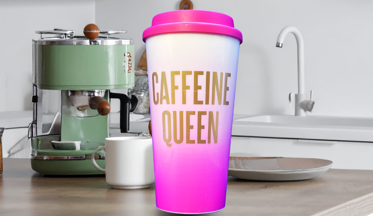 pink caffeine queen tumbler held in hand near coffee maker in kitchen setting