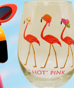 Flamingo wine glass with hats next to flamingo decor and tropical drink