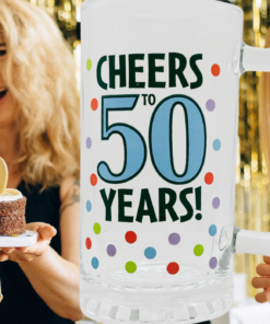 Cheers To 50 Years Beer Mug displayed at a 50th birthday party with gold decorations, birthday cake, and celebrating friends.