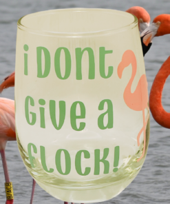 flamingo stemless wine glass with funny phrase placed near real flamingos by the water