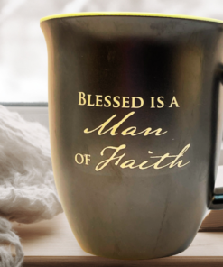 Abbey Press Blessed Is a Man of Faith Mug on table near open book