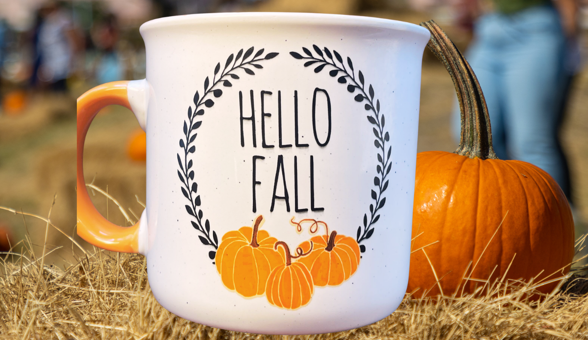 Cynthia Rowley Pumpkin Mug displayed beside an orange pumpkin on hay in an outdoor fall setting