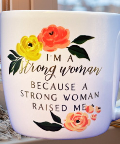Strong Woman Raised Me Coffee Mug styled beside a cozy window with a book and soft blanket