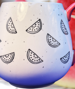 Meritage Watermelon Red Speckled Ceramic Mug displayed with fresh watermelon slices and a coral pink handle