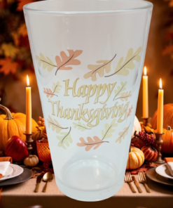 Happy Thanksgiving Drinking Glass displayed at a Thanksgiving table with pumpkins, candles, autumn leaves, and place settings