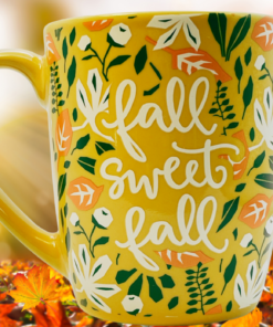 Fall Sweet Fall Mug displayed against a glowing autumn background with colorful fallen leaves