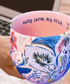 pink mug styled in workspace with laptop book and hand holding mug showing lifestyle use