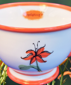 2006 Starbucks Tiger Lily Footed Teacup displayed with orange tiger lilies