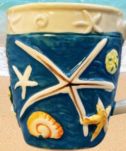 3D Beach Shell Coffee Mug displayed on a sandy beach beside gentle ocean waves