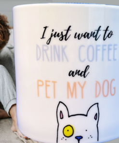 Drink Coffee And Pet My Dog Mug displayed in a cozy indoor scene with a woman holding coffee beside her dog.