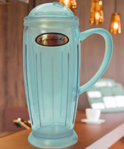 2001 Starbucks Rocket Tumbler displayed in a warm café setting with greenery and hanging lights