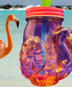 pink flamingo mason jar tumbler on beach with ocean water and flamingo creating tropical summer vibe