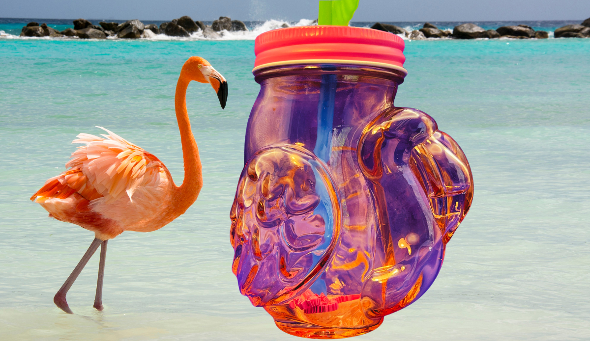 pink flamingo mason jar tumbler on beach with ocean water and flamingo creating tropical summer vibe