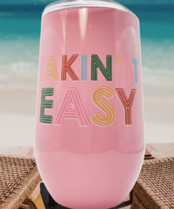 takin it easy pink wine tumbler between beach chairs by ocean