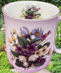 Springfield Purple White Floral mug displayed in a colorful garden setting