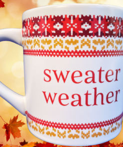 Sweater Weather Knit Pattern Mug displayed against a glowing autumn background with colorful falling leaves