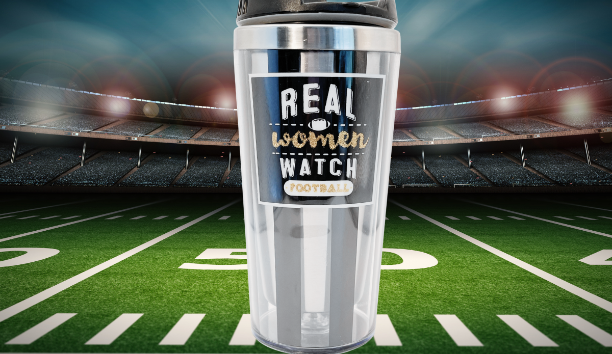 Real Women Watch Football Tumbler displayed on a football field inside a brightly lit stadium
