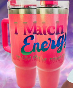 I Match Energy Tumbler lifestyle scene with two coral-pink tumblers and confident woman against colorful purple background