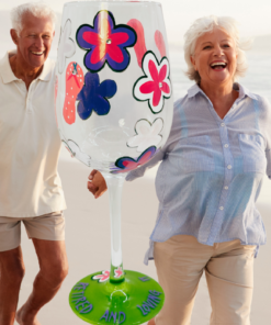 Retired And Loving It Wine Glass displayed with smiling retired couple on beach