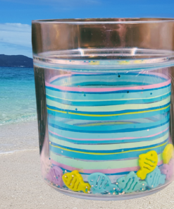 fish acrylic tumbler on sandy beach with turquoise ocean water creating a playful coastal vibe