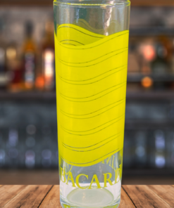 Bacardi Limón Highball Glass displayed on a wooden bar surface with cocktail lounge background