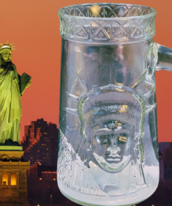 Anchor Hocking Statue of Liberty Centennial Glass Mug displayed beside Lady Liberty against a glowing New York sunset