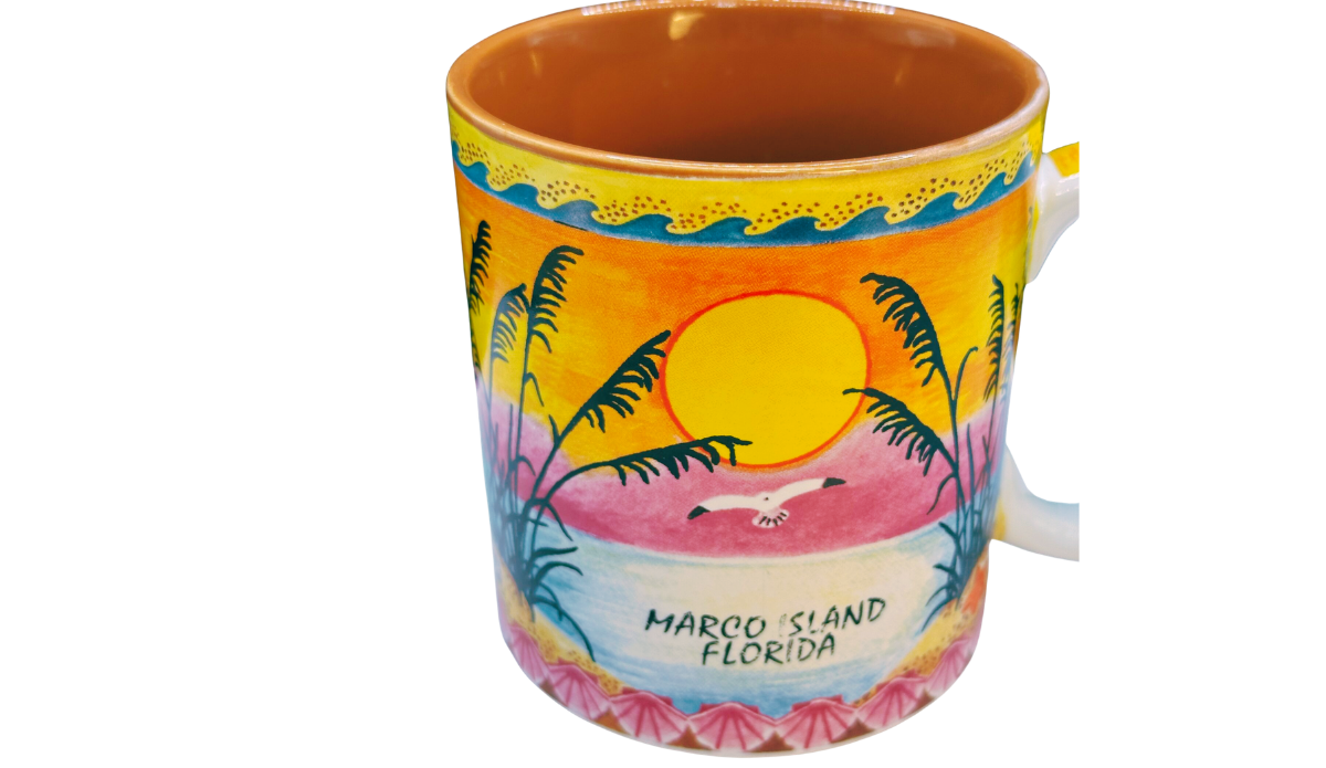Top view of Marco Island Florida souvenir mug showing warm golden glazed interior and tropical sunset artwork around the rim.