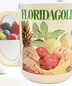 Florida Gold Tropical Fruit Mug styled beside a bowl of fresh oranges kiwi berries and tropical fruit on a bright kitchen counter