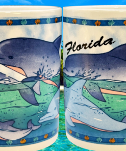 Florida Dolphins Souvenir Mug displayed beside tropical beach decor and coastal background