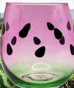 TMD Holdings Watermelon Stemless Wine Glass with a pink and green ombre finish displayed in a watermelon field