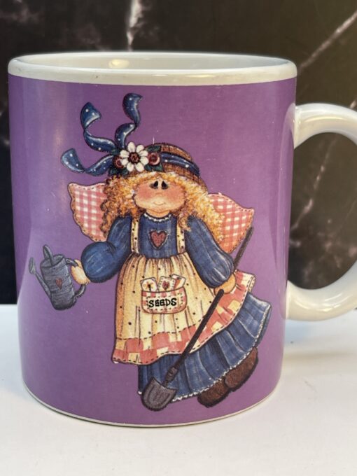 Add heavenly grace and garden magic to your mornings with the Purple Mindy Cain Garden Angel Mug. It's the perfect #cupofmood and serenity in every sip.