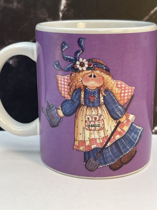 Add heavenly grace and garden magic to your mornings with the Purple Mindy Cain Garden Angel Mug. It's the perfect #cupofmood and serenity in every sip.