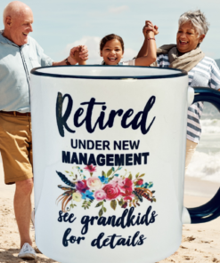 Retired Under New Management Grandkids Mug displayed with grandparents and grandchild on beach