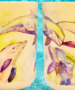 Pastel Dolphin Ceramic Mug showing both sides of the wraparound watercolor dolphin artwork against tropical blue water