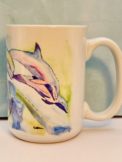 White ceramic mug with pastel colored dolphins swimming around the body