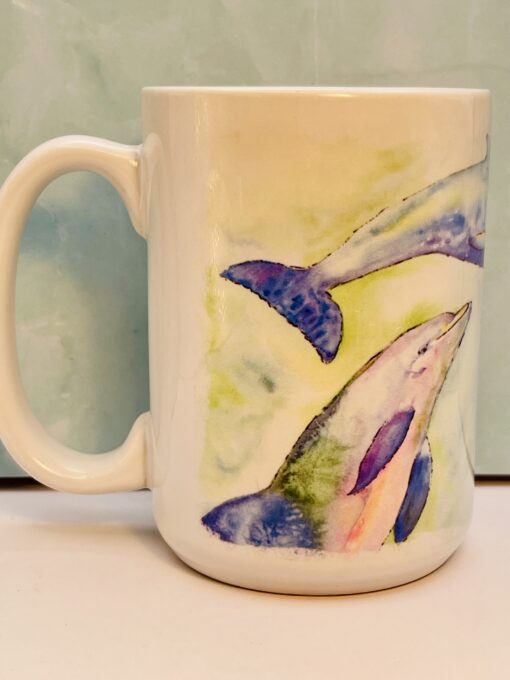 White ceramic mug with pastel colored dolphins swimming around the body