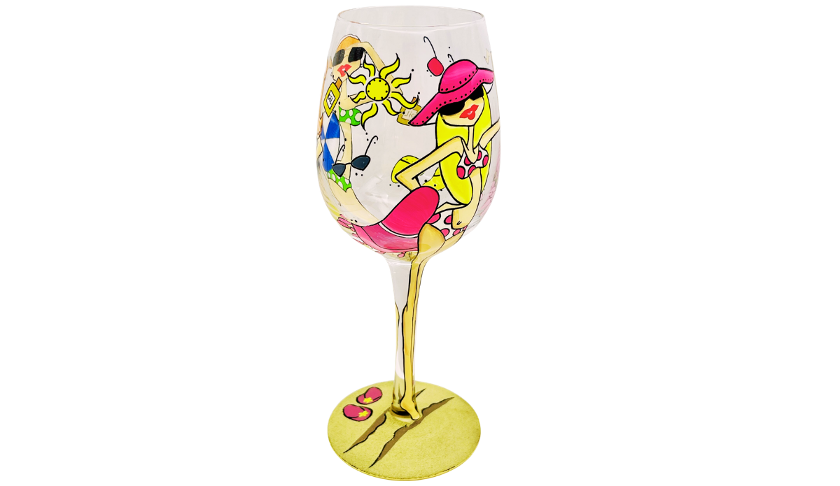Beach Girls Hand Painted Wine Glass showing pink hat beach girl relaxing with second beach girl, sunshine, blue beach ball, sunscreen, sunglasses, and beach accessories